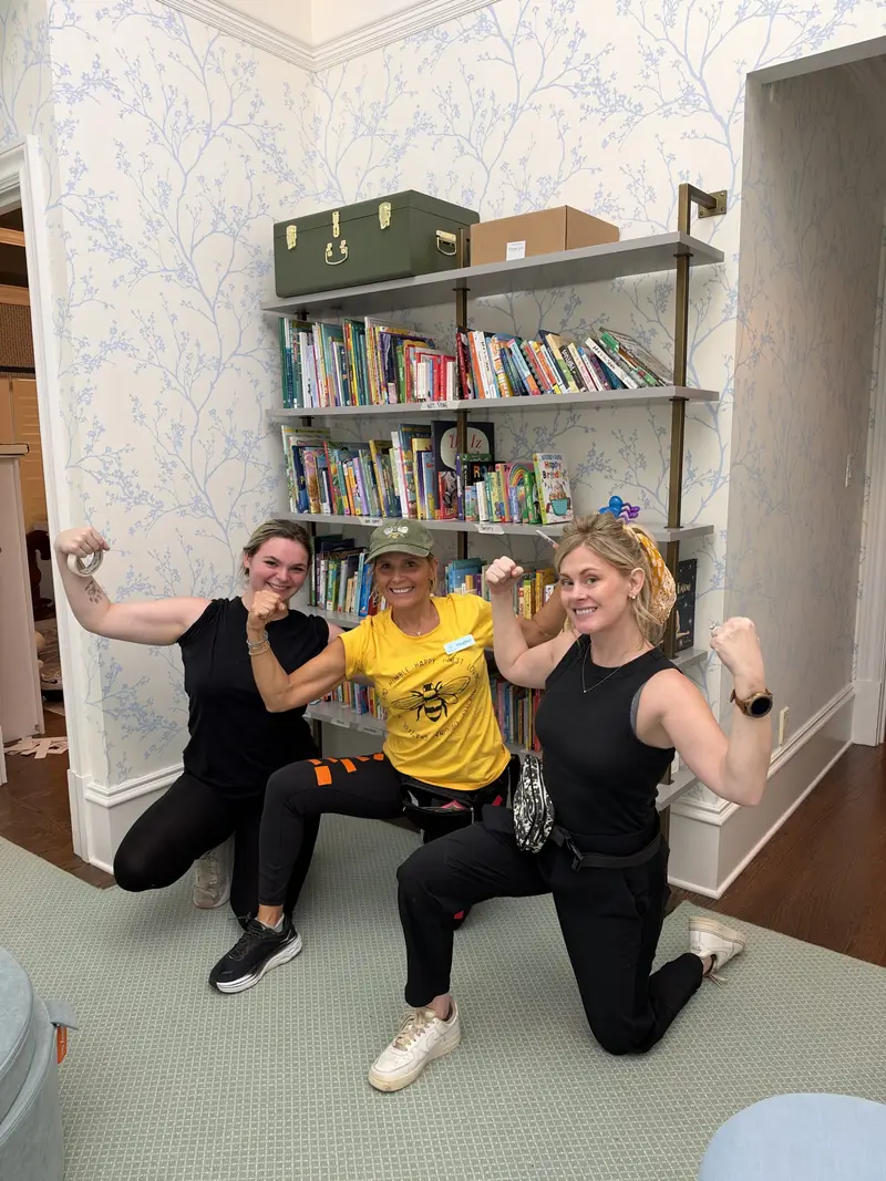 Simply Busy Bee organizers in yellow team shirts posing in front of bookshelves