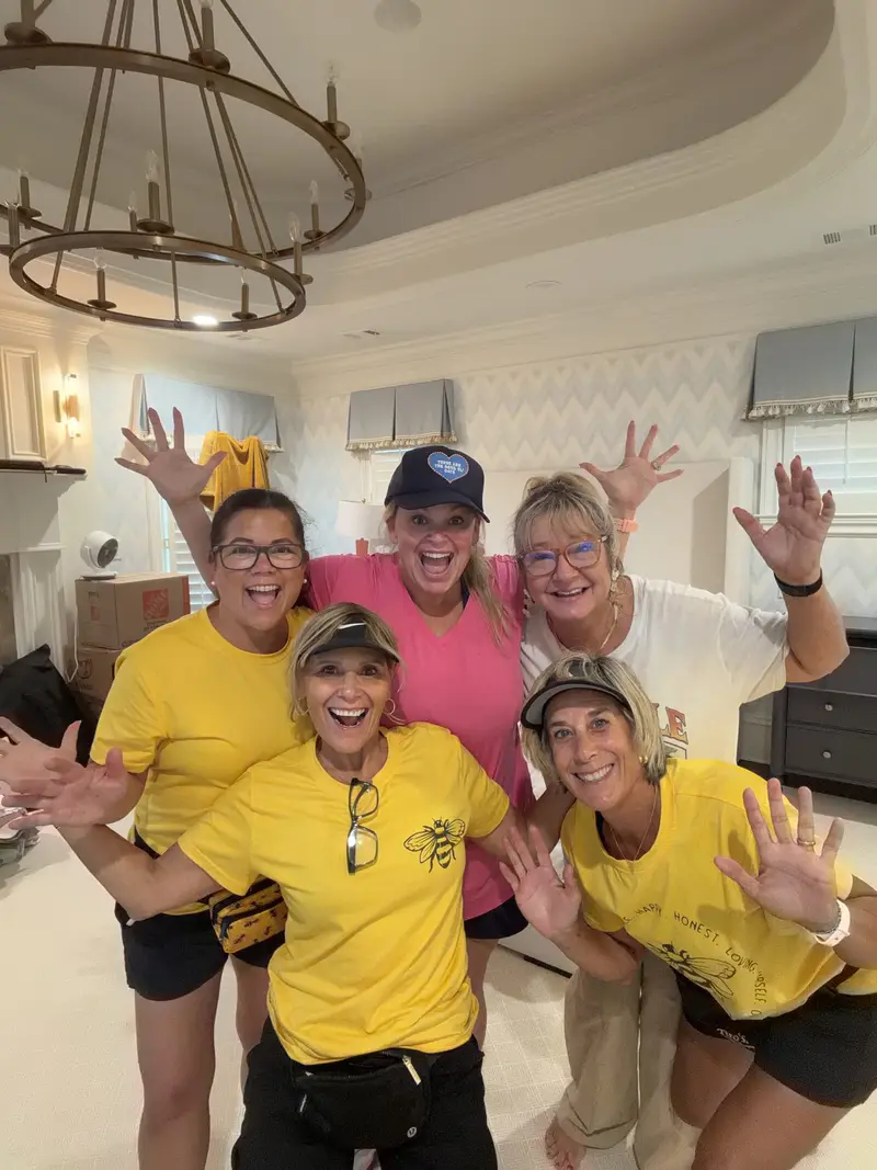 Simply Busy Bee organizers in yellow and black team shirts posing under a chandelier