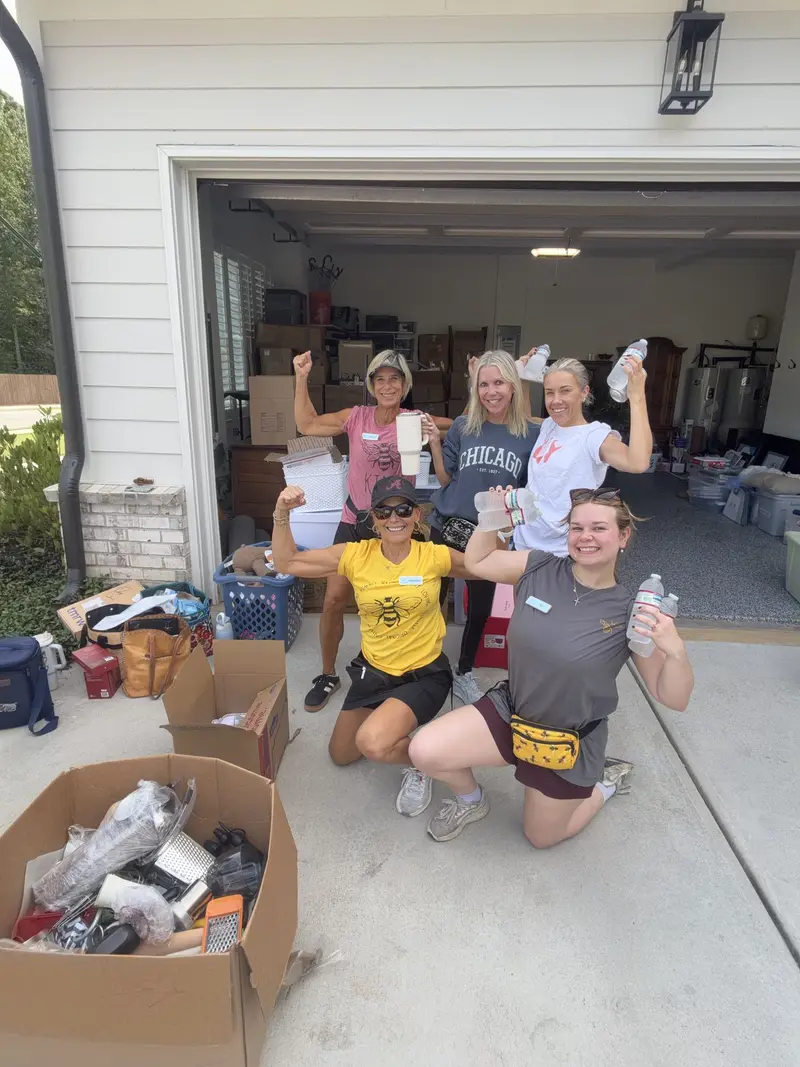Simply Busy Bee organizers in yellow team shirts standing in a garage in front of labeled bins