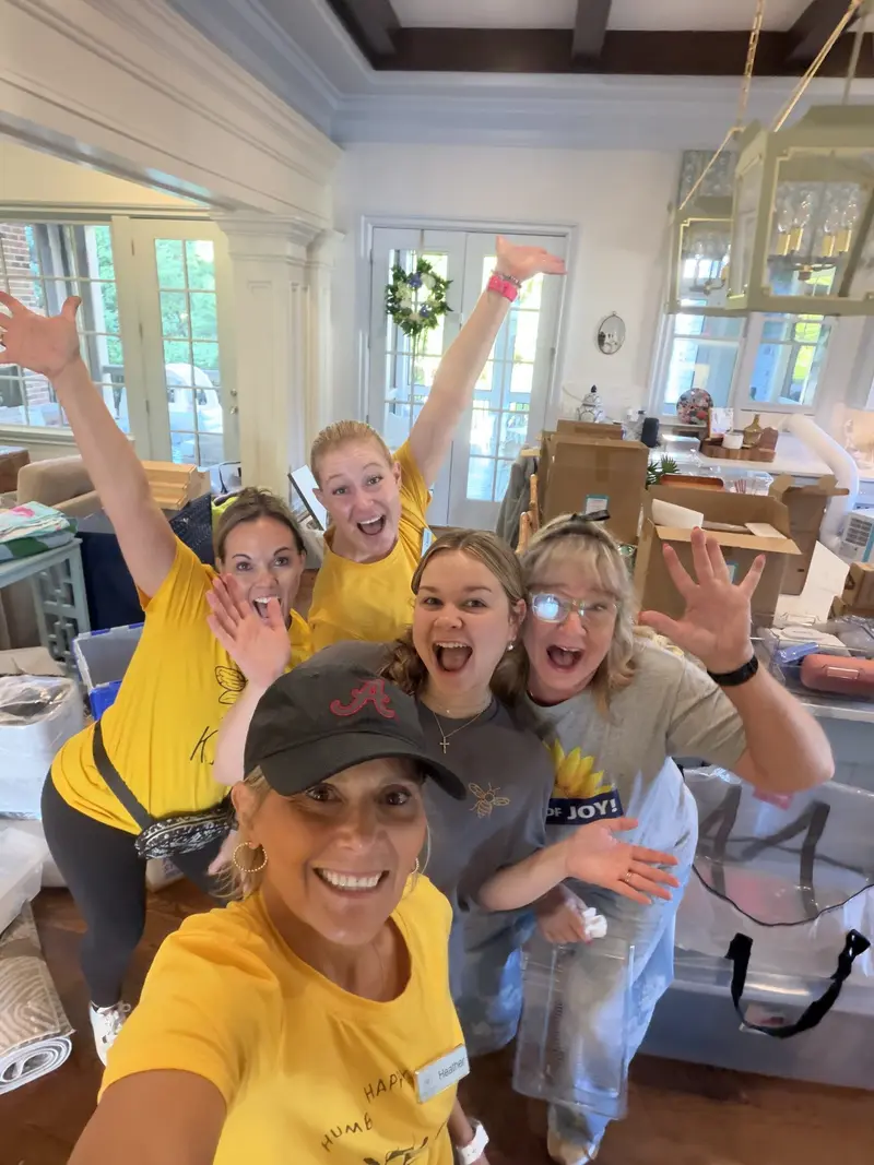 Simply Busy Bee organizers in yellow team shirts taking a group selfie in a home