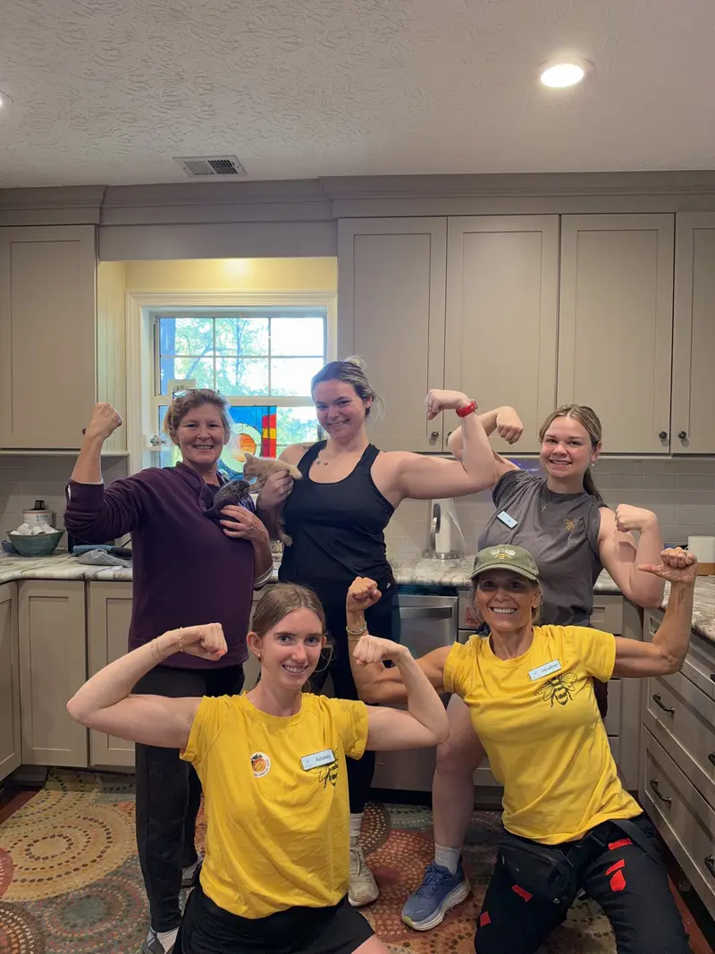 Simply Busy Bee organizers in yellow team shirts flexing in a kitchen