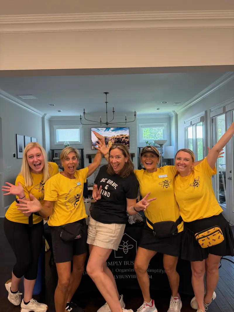 Simply Busy Bee organizers in yellow and black team shirts posing in a living room