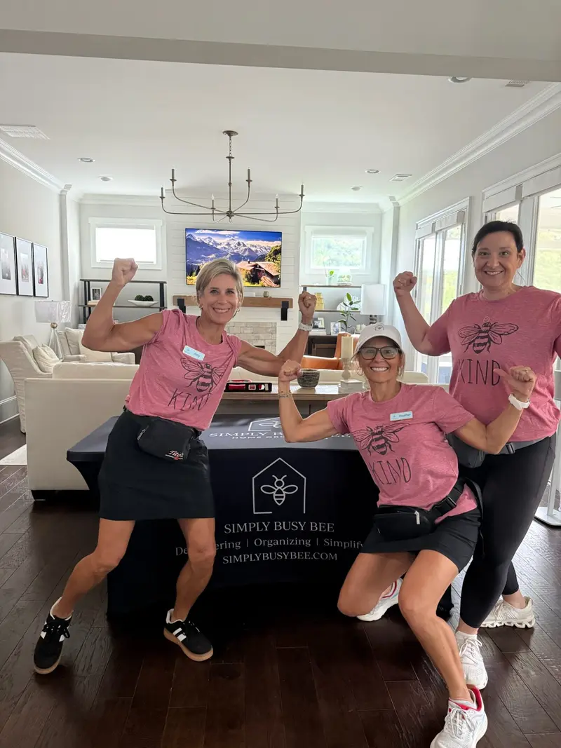 Simply Busy Bee organizers in pink team shirts flexing in a living room